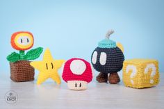 crocheted toys are lined up on a table with star and mushroom decorations in the background