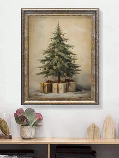 a christmas tree with presents under it on a shelf in front of a framed painting