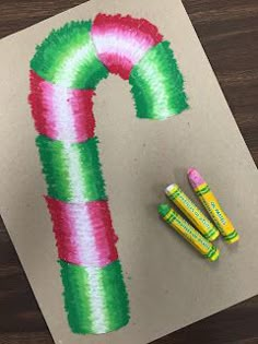 some crayons are laying next to a candy cane on a piece of paper