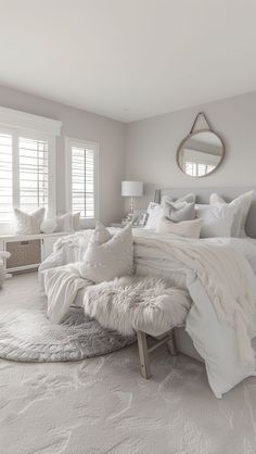 a large white bed sitting in a bedroom on top of a floor next to a window