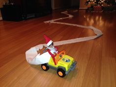 the elf is driving his toy car on the floor