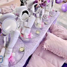 a purple table topped with plates and bowls filled with food next to balloons in the background