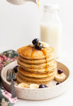 a stack of pancakes with syrup being poured on top