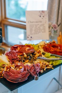 an assortment of meats and cheeses on a buffet table with utensils