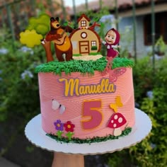 a pink birthday cake with cartoon characters on top and the number five is for manuelella