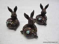 three chocolate bunnies sitting on top of each other with flowers painted on the tops