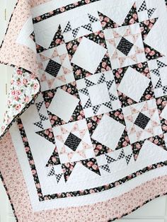 a quilt is hanging on the wall next to a white door with pink and black flowers