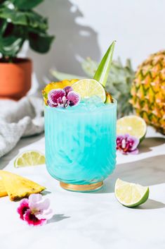 a blue drink with lemons, pineapple and orchid on the table next to it