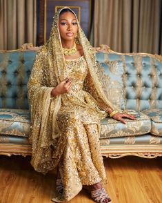 a woman sitting on top of a couch wearing a gold dress and headpieces