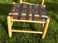 a wooden chair made out of old leathers on the grass in front of some trees