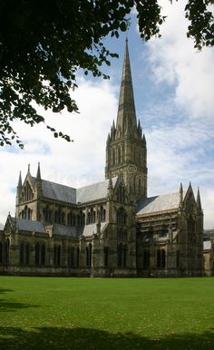 an old building with a steeple on the top and green grass in front of it