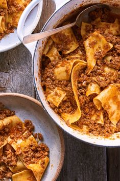 two bowls filled with pasta and meat on top of a wooden table