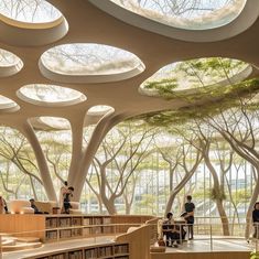 people are sitting at tables in the middle of an open air library with trees on both sides