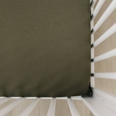 a close up view of the side of a baby crib with an olive green cover