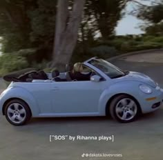 a blue convertible car driving down a street