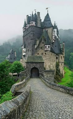 an old castle is shown on the side of a hill with cobblestone roads