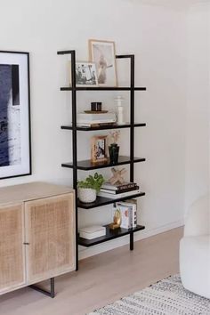 a living room with a white couch and black shelving unit next to a painting on the wall