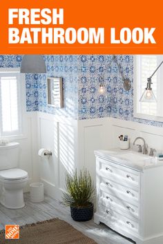 a bathroom with blue and white wallpaper has a plant next to the sink in front of it