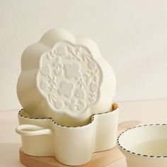 a white cup and saucer sitting next to each other on a wooden stand in front of a wall