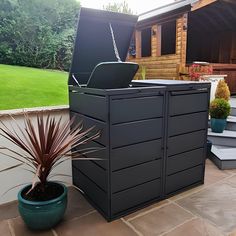 an outdoor storage unit with a laptop on top and a potted plant next to it