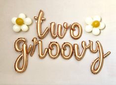 the words two groovy are made out of gold foil balloons and daisies