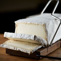 a piece of cheese sitting on top of a wooden cutting board