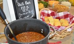 a pot filled with chili next to a chalkboard sign