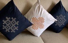 three decorative pillows sitting on top of a couch