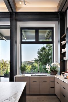 a modern kitchen with marble counter tops and stainless steel appliances in front of a large window