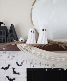 two ghost decorations sitting on top of a mantle