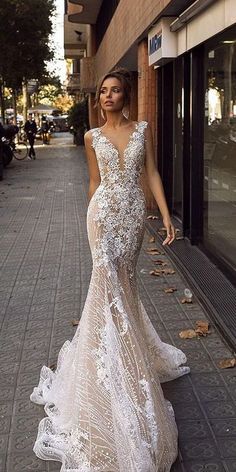 a woman in a wedding dress standing on the side of a street next to a building