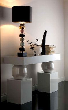 a white table with two vases and a black lamp on it's side