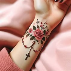 a woman's arm with a rose and cross tattoo on the left side of her wrist