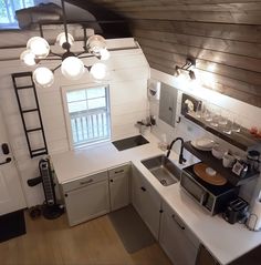 an overhead view of a kitchen with white counter tops and cabinets, along with a ladder leading up to the ceiling