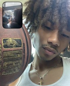 a man with dreadlocks and a cross on his arm holding up a football