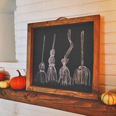 a chalkboard with three brooms drawn on it next to pumpkins and gourds