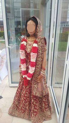 a mannequin dressed in a red and gold bridal gown stands next to a window