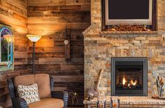 a living room with a fire place and two chairs in front of a tv mounted on the wall