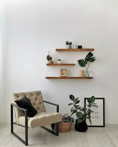 a living room with white walls and wooden shelves on the wall, a chair in front of a potted plant