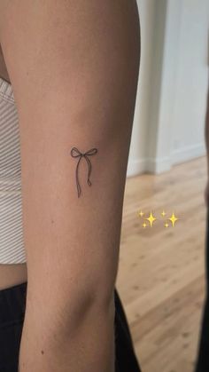 a woman's arm with a tattoo on it that has a bow at the top