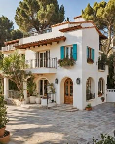 a large white house with blue shutters and potted plants on the front porch