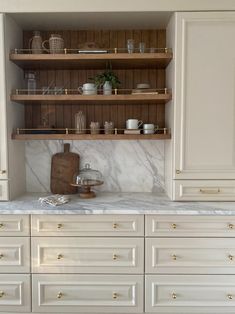 a kitchen with white cabinets and marble counter tops, gold hardware on the upper shelves