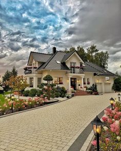 a white house with lots of flowers in the front yard and walkway leading up to it