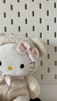 a white hello kitty stuffed animal sitting on top of a shelf with holes in the wall behind it