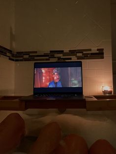 a laptop computer sitting on top of a bath tub filled with water and lit candles