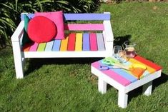 a colorful bench and footstool in the grass with a glass of wine on it