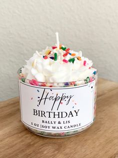 a birthday candle with sprinkles in a glass container on a wooden table