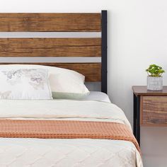 a bed with a wooden headboard next to a night stand and small plant on the nightstand