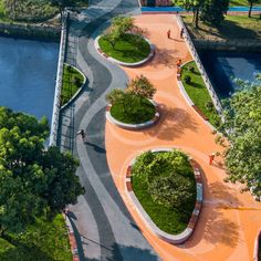 an aerial view of a park with trees, water and people walking on the path