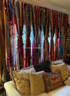 a living room filled with lots of different colored ties hanging on the wall behind a couch